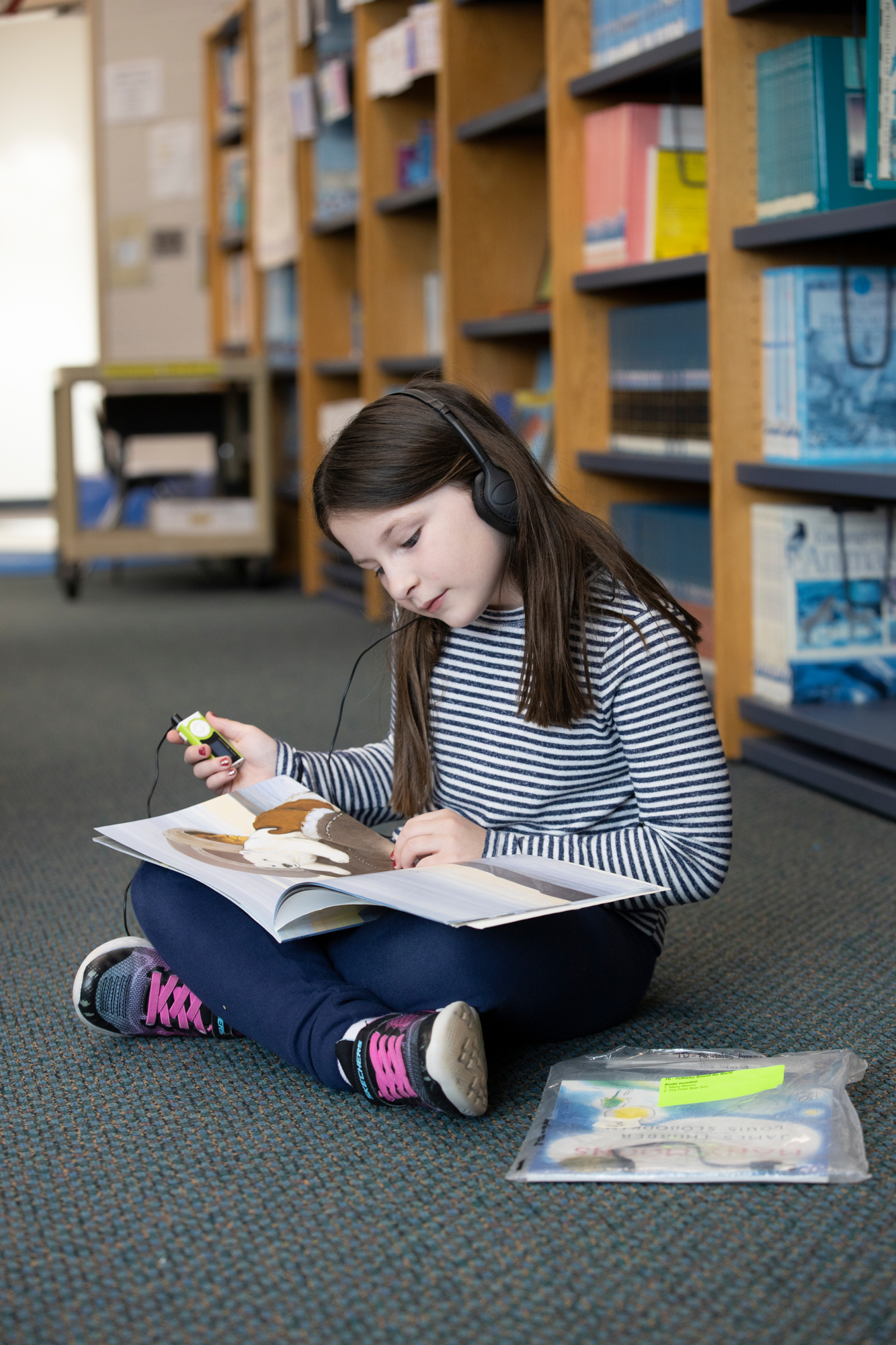 Ava-pictured-here-in-ERfCs-After-School-Center-is-listening-to-a-CRISKids-audio-book-on-an-MP3-player-while-following-along-in-the-print-version-of-the-book