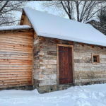 Noah Blakes cabin in winter with a snow covered roof and ground cover in snow